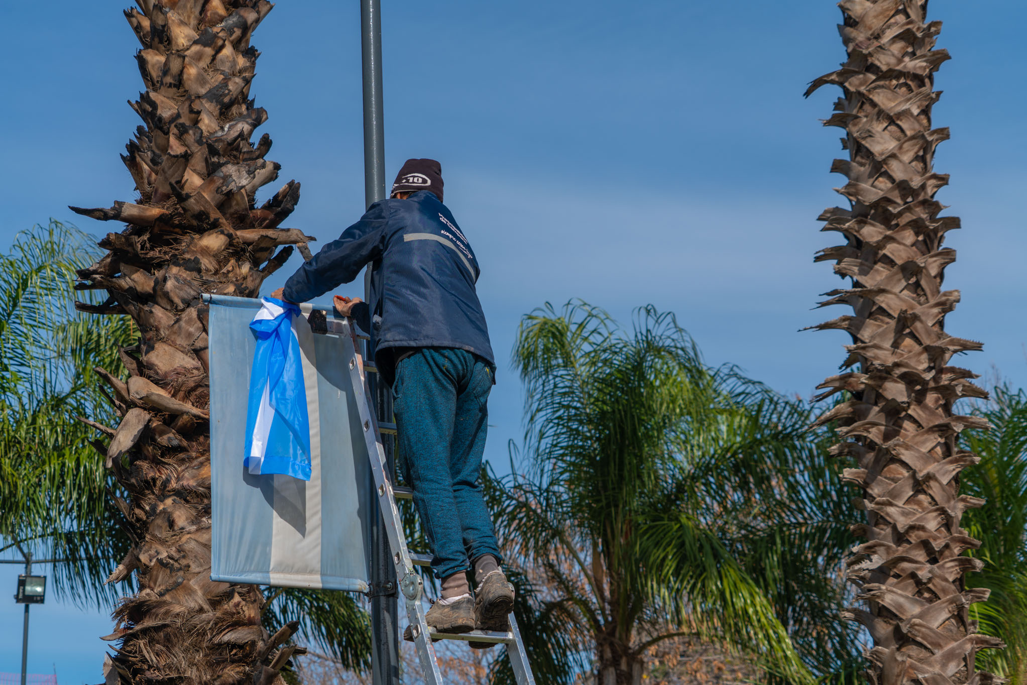 Empleado municipal cambiando bandera vieja por nuevo