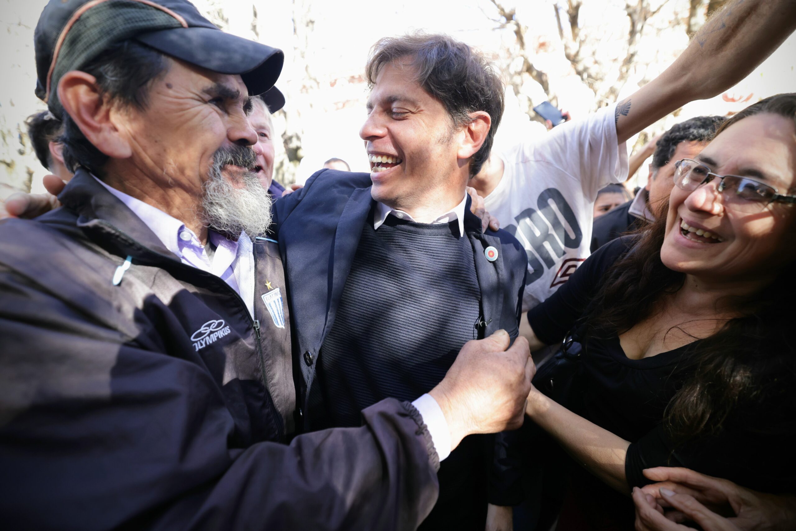 Kicillof abrazanddose con la gente que le sonrie feliz